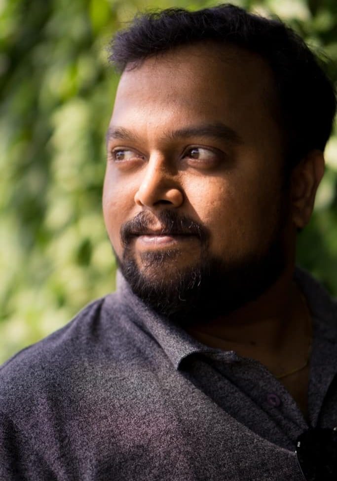 Indian man with beard and moustache portrait with natural light and a green bokeh backround